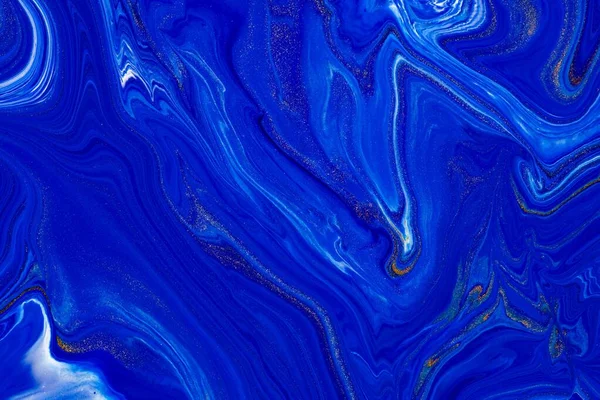 Fluid art texture. Abstract backdrop with swirling paint effect. Liquid acrylic artwork that flows and splashes. Classic blue color of the year 2020. Blue, golden and white overflowing colors.