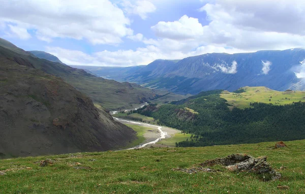 Yazın Altai 'deki Karagem Geçidi' ndeki Dzhelo Nehri 'nin uzak bir manzarası. Nehir vadisinde, sağ yamaçlarda bir orman, büyük dağ sıraları, bulutlu bir gökyüzü var.