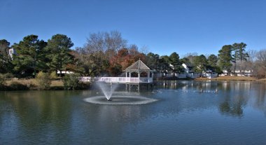 Arka planda bir çardağı olan göldeki çeşme.