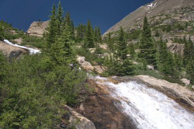 Su kayalık araziye hücum ederken küçük miktarda kar hala etrafta dolanıyor.