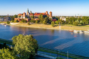 Wawel Katedrali ve Krakow, Polonya 'daki kale. Gün batımında hava manzarası. Vistula Nehri, turist tekneleri, kanolar, ağaçlı nehir kıyıları, parklar, gezinti güvertesi ve yürüyen insanlar.