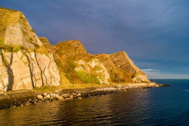 Kuzey İrlanda, İngiltere. Atlantik kıyısı. Cliffs ve Antrim Coast Road, namı diğer. Causeway Sahil Yolu. Avrupa 'nın en manzaralı kıyı yollarından biri. Güneş doğarken Garron Point yakınlarında hava manzarası