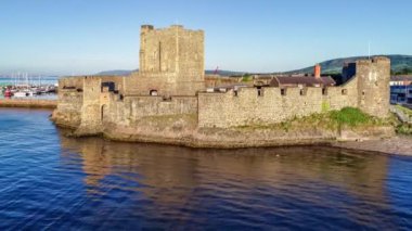 Ortaçağ Norman Kalesi ve Carrickfergus Limanı. Gün doğumunda Belfast yakınlarında. Marinayla, yatlarla, dalgakıranlarla ve kasabayla hava 4K izleme videosu.
