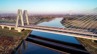 Polonya 'nın Krakow kentindeki Vistula Nehri üzerindeki yeni modern çift kablolu köprü ve gündoğumunda sudaki yansıması. Krakow çevresindeki çevre yolunun bir parçası. Hava 4K görüntüsü