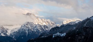 Dolomitler, İtalya. Gün doğumunda sisli bir ortamda Civetta Dağı kitlesi Arabba yakınlarındaki Pieve di Livinalongo 'dan ve Chiesa di Val' deki tepedeki kiliseden izleniyor. Geniş görünüm