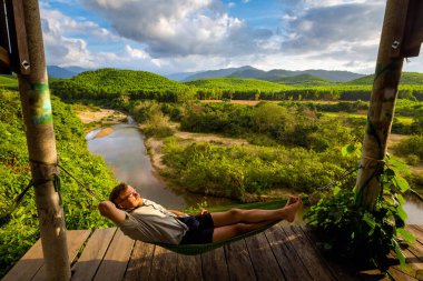 Vietnam 'daki Ulusal Park Phong Nha Ke Bang' de hamakta dinlenen güzel beyaz tenli bir turist. Güneydoğu Asya 'da çekilmiş kırsal manzara fotoğrafı. Vietnam' ın en güzel yerlerinden biri..