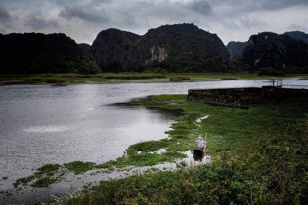 Beautiful landscape with fishing person in Van Long Nature Reserve, Tam Coc, Ninh Binh in Vietnam. Rural scenery photo from the boat taken in south east Asia.
