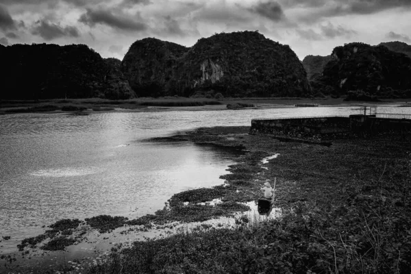 Beautiful landscape with fishing person in Van Long Nature Reserve, Tam Coc, Ninh Binh in Vietnam. Rural scenery black and white photo taken in south east Asia.