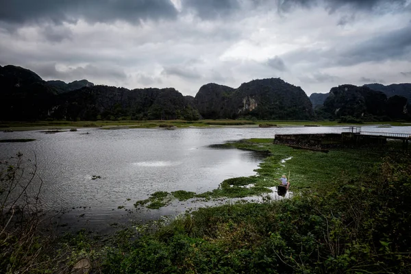 Beautiful landscape with fishing person in Van Long Nature Reserve, Tam Coc, Ninh Binh in Vietnam. Rural scenery photo from the boat taken in south east Asia.