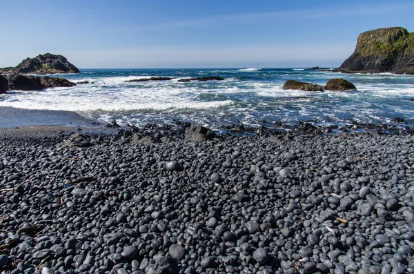 Black pebble beach on pacific coast — Stock Photo, Image