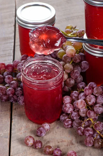 Jars of jelly and grapes with spoon — Stock Photo, Image