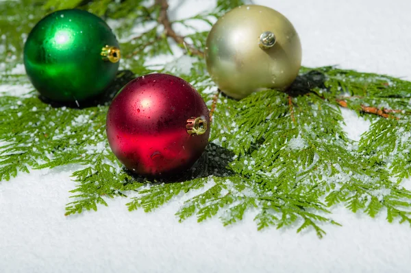 Drie kerstballen in de sneeuw met ceder — Stockfoto