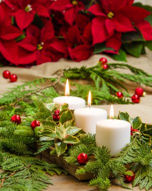 Herdem yeşil ve poinsettias ile yanan mumlar