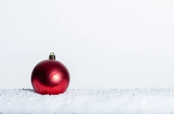 Ornamento de Natal vermelho único na neve — Fotografia de Stock