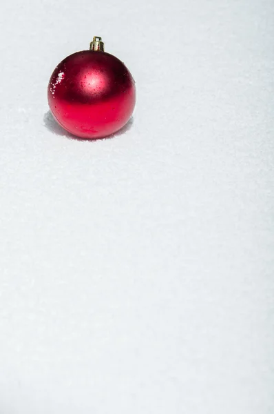 Adorno rojo de Navidad en la nieve —  Fotos de Stock