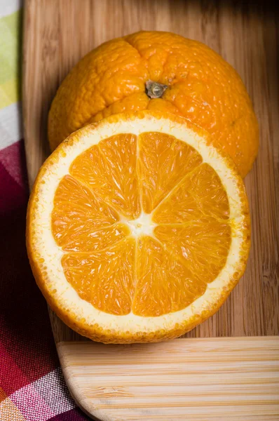 Laranja cortada ao meio na tábua de corte — Fotografia de Stock