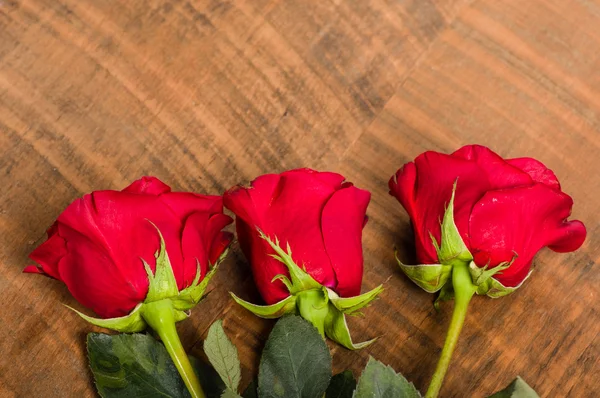 三朵红玫瑰放在桌子上 — 图库照片