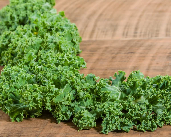 Curly kale leaves on wooden table — Stock Photo, Image