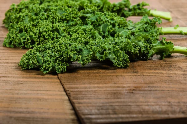 Green curly kale leaves on table — Stock Photo, Image