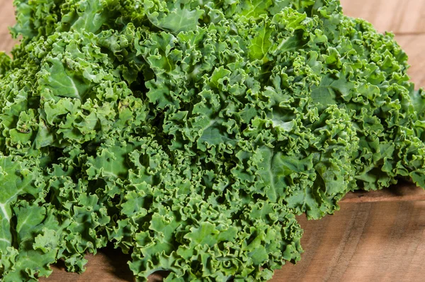 Curly kale leaves on wooden table — Stock Photo, Image