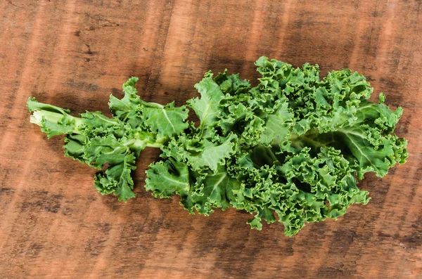 Curly kale leaves on wooden table — Stock Photo, Image