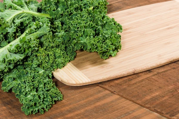 Curly kale leaves on cutting board — Stock Photo, Image