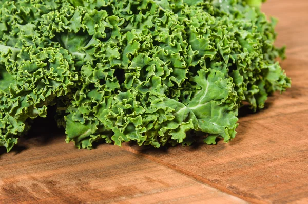 Curly kale leaves on wooden table — Stock Photo, Image