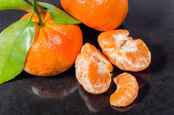 Ripe tangelos with leaves on black counter — Stock Photo, Image