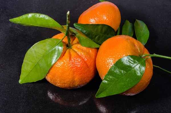 Ripe tangelos with leaves on black counter — Stock Photo, Image
