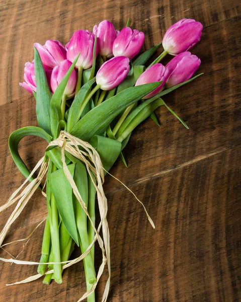 Buquê de tulipas rosa em uma mesa de madeira — Fotografia de Stock