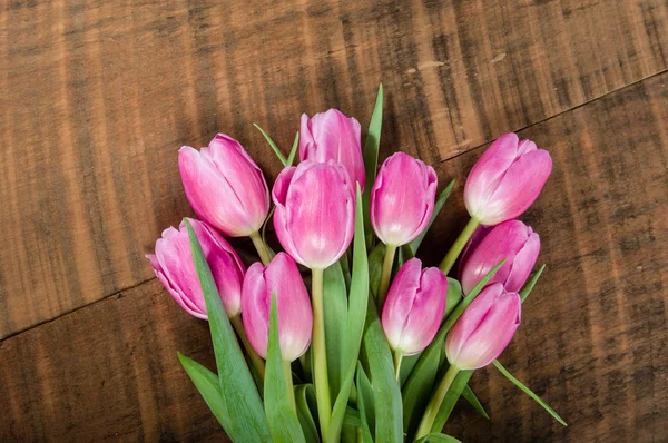 Buquê de tulipas rosa em uma mesa de madeira — Fotografia de Stock