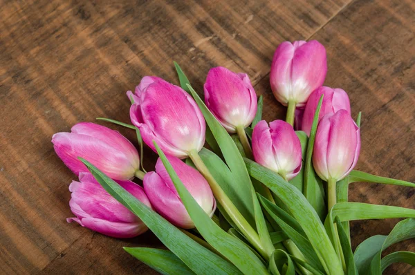 Buquê de tulipas rosa em uma mesa de madeira — Fotografia de Stock