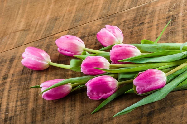 Buquê de tulipas rosa em uma mesa de madeira — Fotografia de Stock