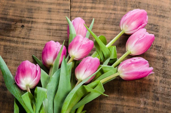 Buquê de tulipas rosa em uma mesa de madeira — Fotografia de Stock