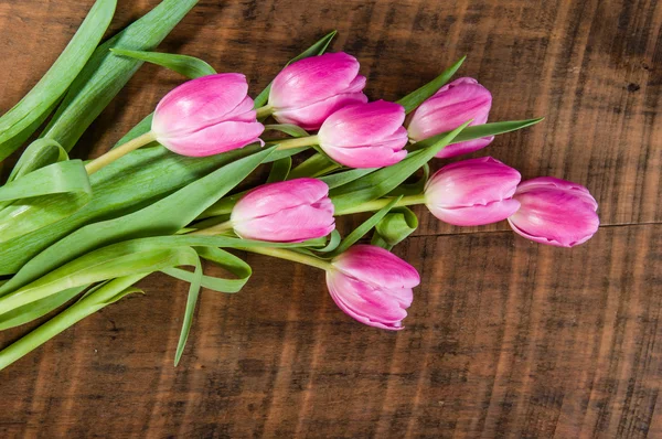 Buquê de tulipas rosa em uma mesa de madeira — Fotografia de Stock