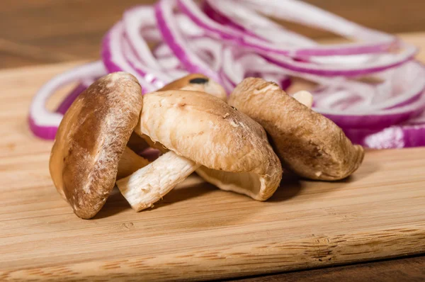 Champiñones y cebollas rojas en la tabla de cortar — Foto de Stock