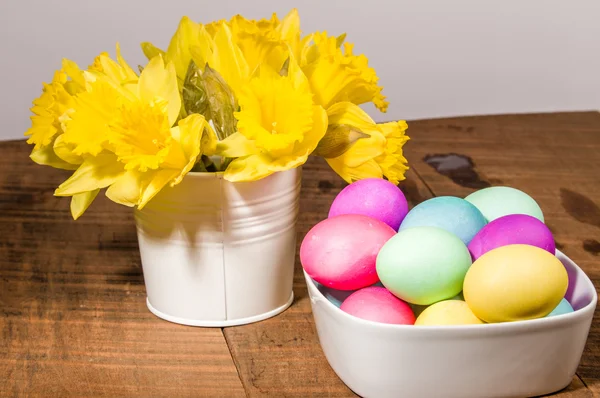 Bowl of dyed eggs with vase of flowers — Stock Photo, Image