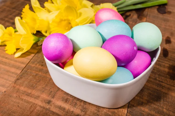 Bowl of dyed Easter eggs with daffodils — Stock Photo, Image