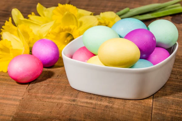 Bowl of dyed Easter eggs with daffodils — Stock Photo, Image