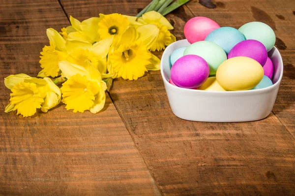 Bowl of dyed Easter eggs with daffodils — Stock Photo, Image