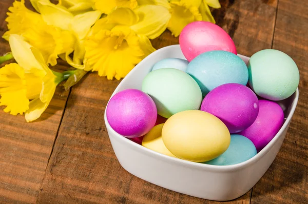 Skål med färgade påskägg med påskliljor — Stockfoto