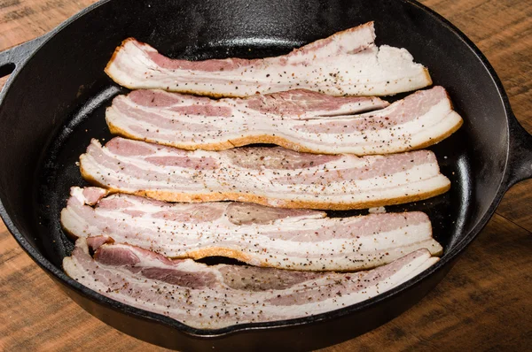 Stekpanna med rader av rå bacon — Stockfoto