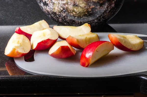 Нарезанные красные яблоки на доске с миской — стоковое фото