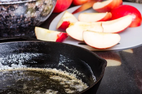 Сковородка с растопленным маслом и красными яблоками — стоковое фото