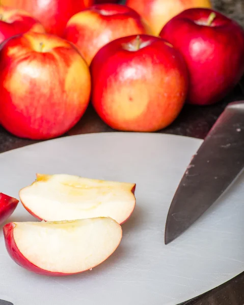 Вырезать красные яблоки ножом — стоковое фото