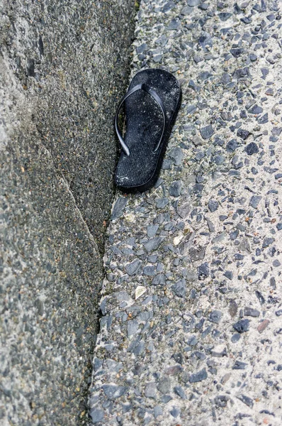 Abandoned black flip flop shoe — Stock Photo, Image