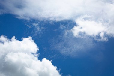 Yumuşak beyaz bulutlu mavi gökyüzü, yakın planda, huzur, özgürlük ve çevresel güzelliği sembolize eden sakin ve ferahlatıcı bir doğal zemin oluşturuyor..