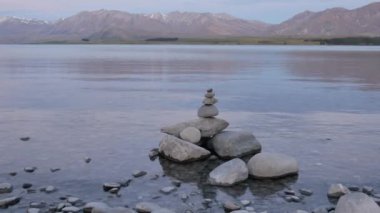 Tekapo Gölü 'ndeki Zen taşı, arka plandaki John Dağı' nı yansıtıyor..