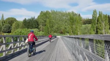 Old Love Shotover Köprüsü 'nde insanlar bisiklet sürüyor.