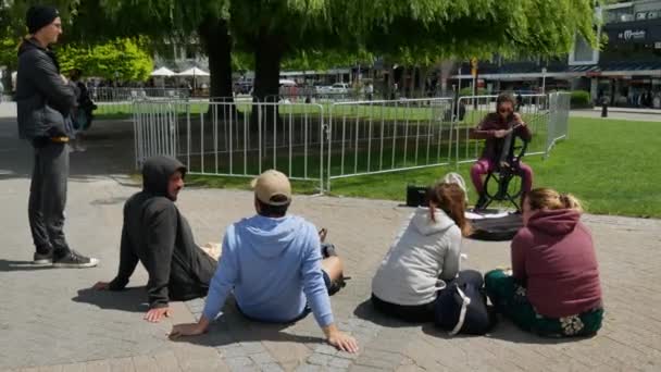 Turis duduk di lantai menikmati mendengarkan musik dimainkan oleh biola wanita busker. — Stok Video